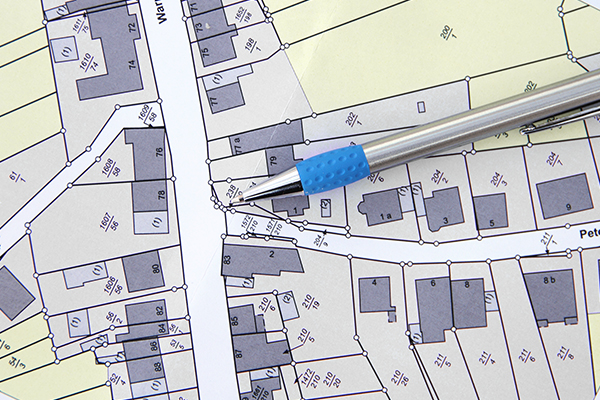 A pen resting on a parcel map of a neighborhood.