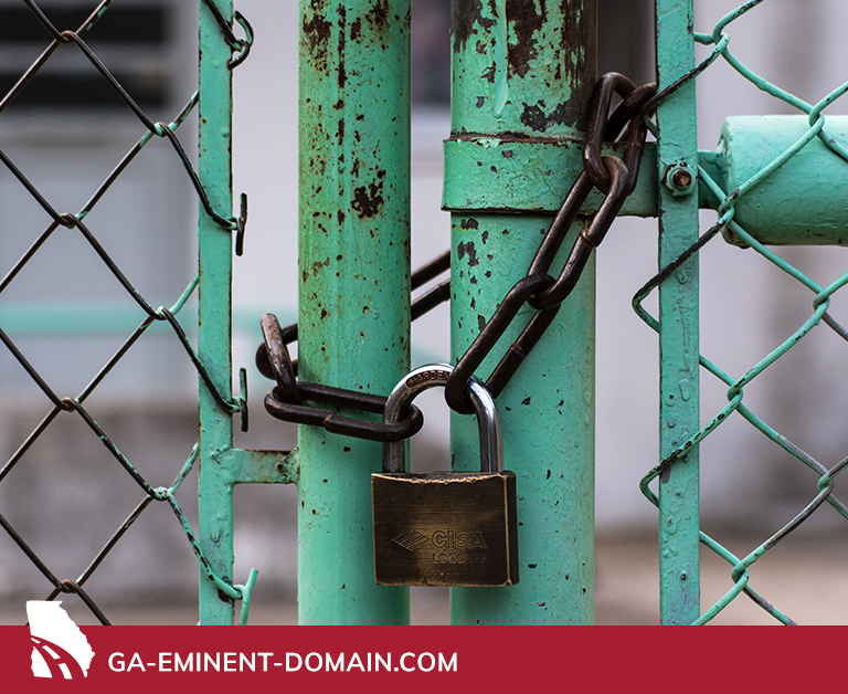 Large padlock chained to a green iron chain link gate.