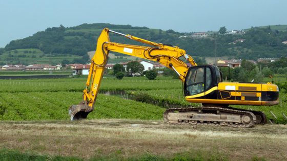 Heavy machinery digging near the edge of a farm property.