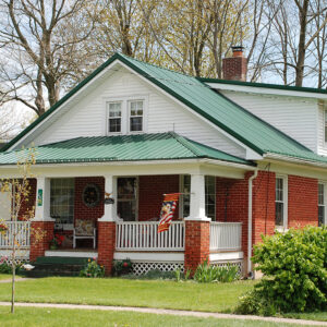 A small house with a green roof and brick facade in the suburbs.ALT TEXT: A small house with a green roof and brick facade in the suburbs.