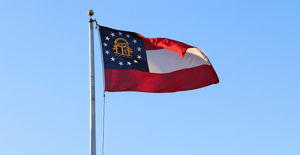 The flag of the state of Georgia flying against a blue sky in the United States.