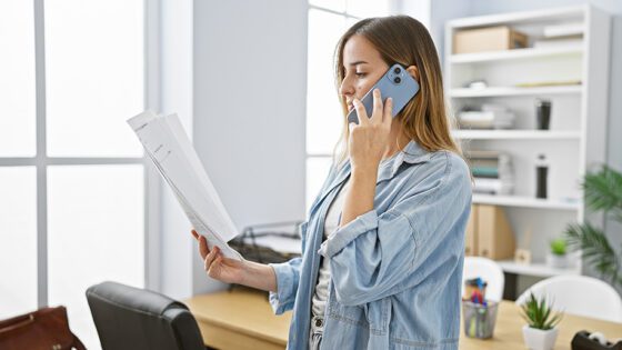 Concerned woman going over paperwork on the phone at her office.